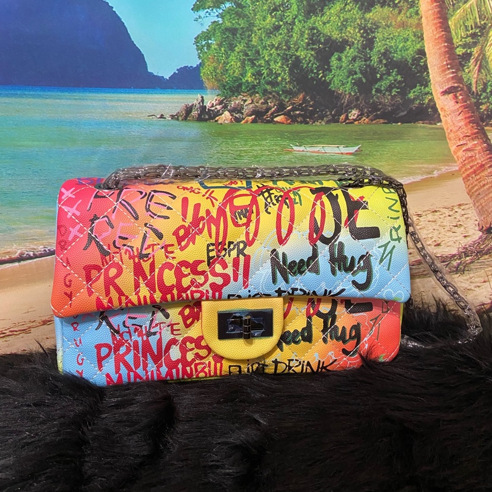 Large graffiti handbag with black chain strap.